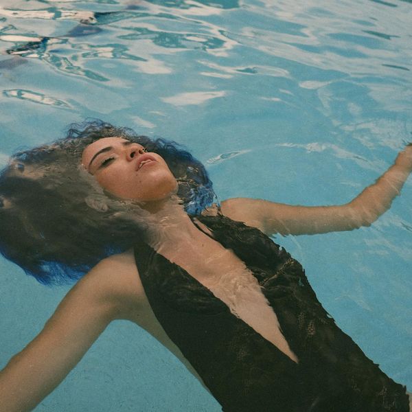 Person stretching peacefully outdoors near a body of water.